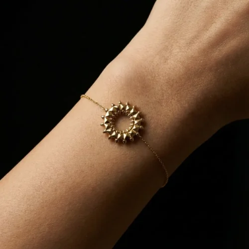Bracelet fin acier doré avec médaillon rond à picots pyramidaux porté au poignet, style lifestyle, Scoobijou Maroc.