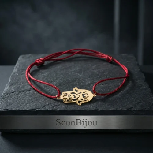 Bracelet porte-bonheur en cordon rouge ajustable avec un pendentif central en forme de Khamsa (Main de Fatma) finement découpé en Or 18 carats sur un fond noir luxueux.