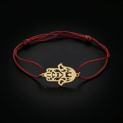 Bracelet porte-bonheur en cordon rouge ajustable avec un pendentif central en forme de Khamsa (Main de Fatma) finement découpé en Or 18 carats sur un fond noir luxueux.