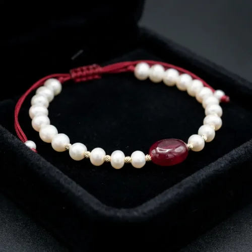 Bracelet ajustable sur cordon rouge avec perles d'eau douce جوهر حر, boules en or 18k et pierre centrale rouge au Maroc.