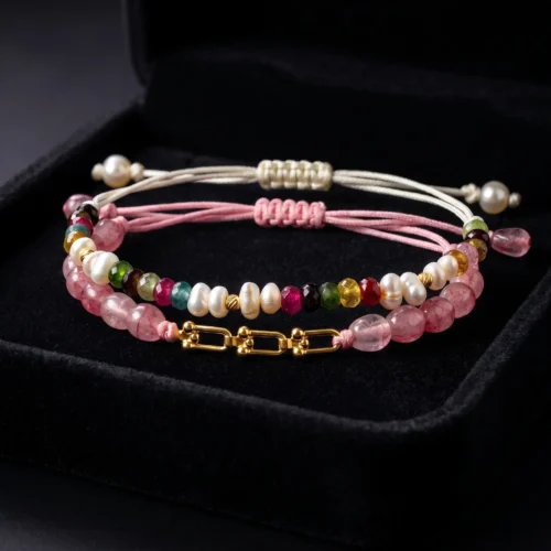 Duo de bracelets ajustables en macramé présentés dans un écrin noir, ornés de véritables perles d'eau douce, de tourmalines multicolores et roses, et de maillons en or 18K.