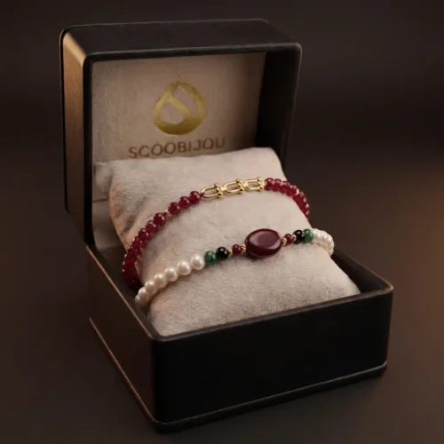 Duo de bracelets ajustables en macramé avec véritables perles d'eau douce, émeraude synthétique, pierres rouges et finitions en or 18K dans un écrin noir.