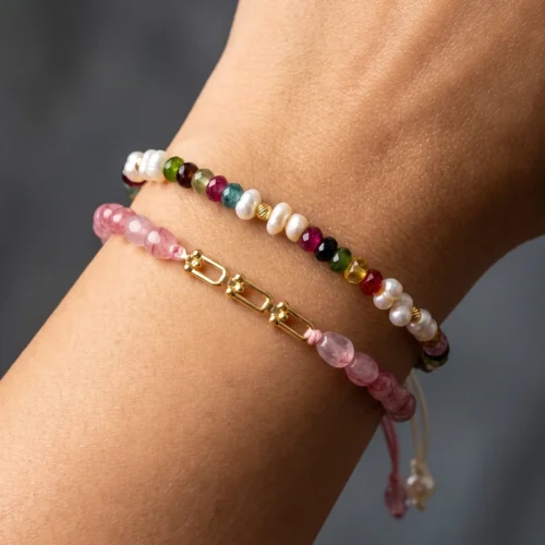 Duo de bracelets ajustables en macramé présentés dans un écrin noir, ornés de véritables perles d'eau douce, de tourmalines multicolores et roses, et de maillons en or 18K.