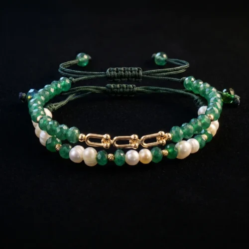 Duo de bracelets ajustables en macramé vert foncé ornés de véritables perles d'eau douce, de pierres vertes facettées et de finitions géométriques en or 18K, présentés dans un écrin noir.